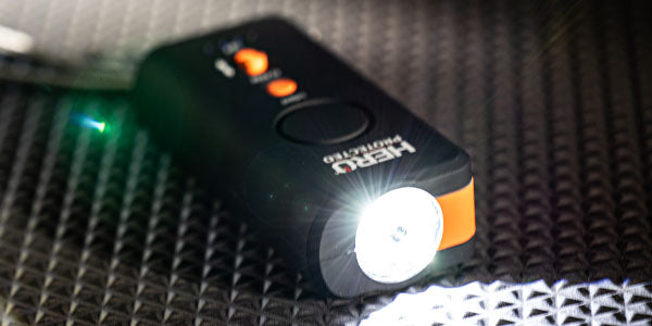 A HEROLITE 4-in-1 Siren sits on a table at night, it's bright flashlight illuminated