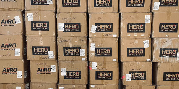 A stack of shipping boxes with HERO Non-Lethal and AIIRO Non-Lethal branding